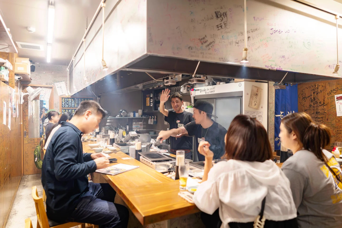 바 테이블에서 식사하는 손님들과 손을 흔드는 직원