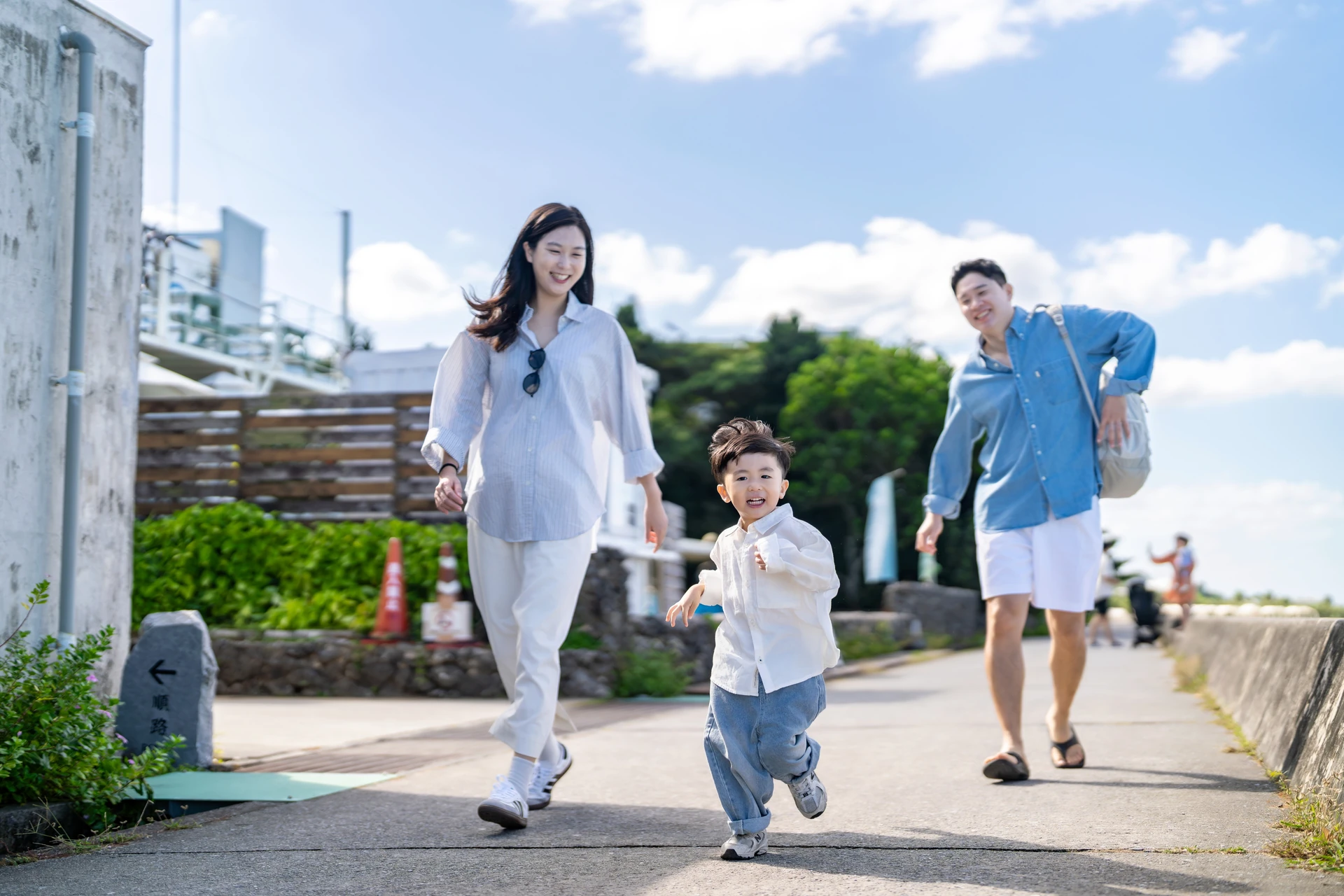 산책로를 신나게 달려오는 아이와 뒤따라 뛰는 엄마와 아빠