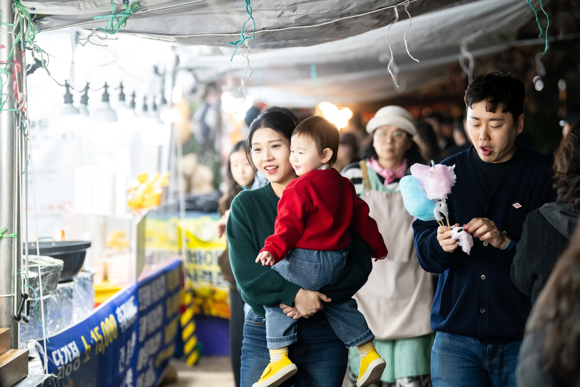 야시장 인파 속에서 솜사탕을 든 가족