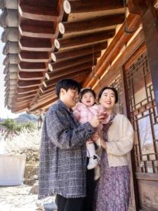 한옥 처마 아래에서 아기를 안은 엄마와 아빠