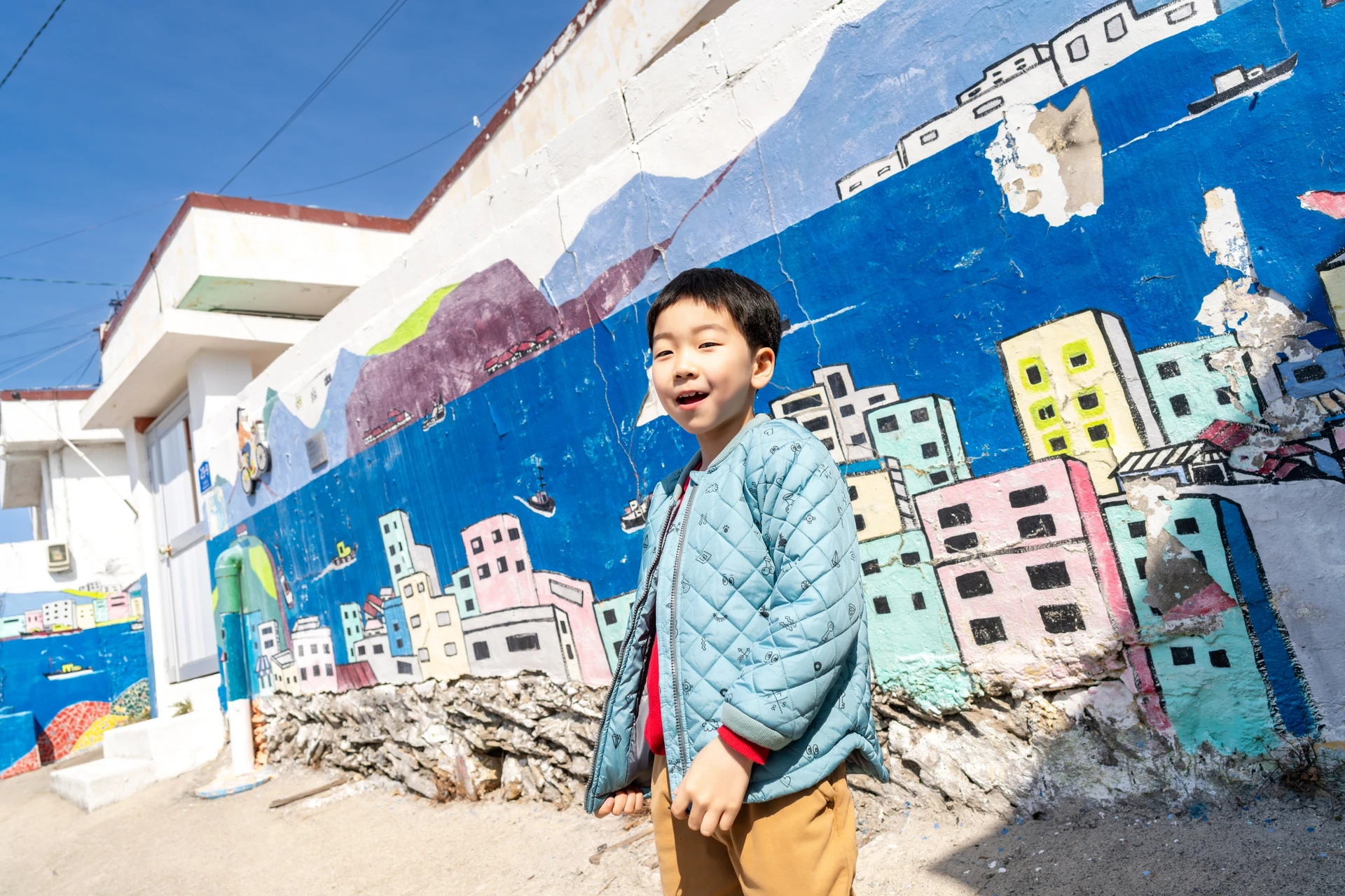 도시 벽화 앞에 선 남자아이
