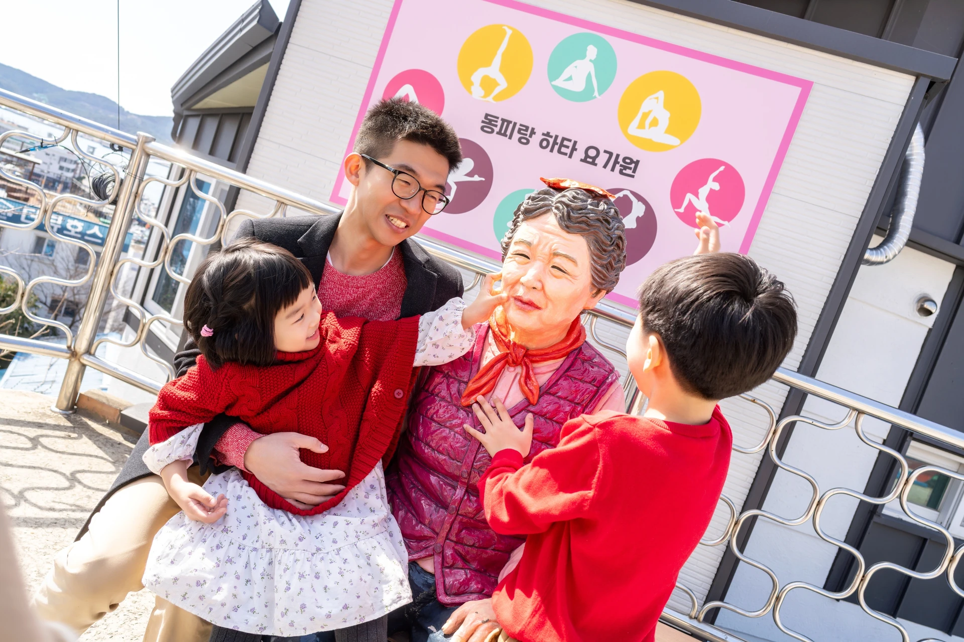 할머니 조형물 옆에서 웃는 가족