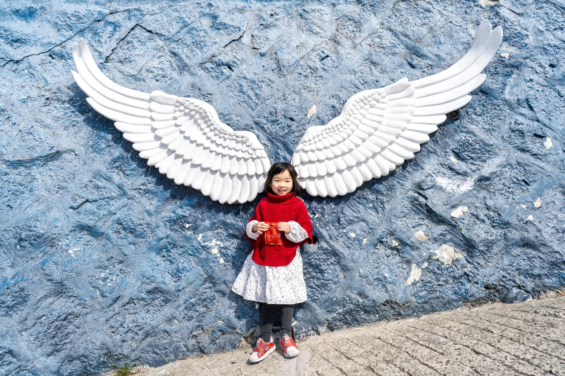날개 벽화 앞에 서 있는 여자아이