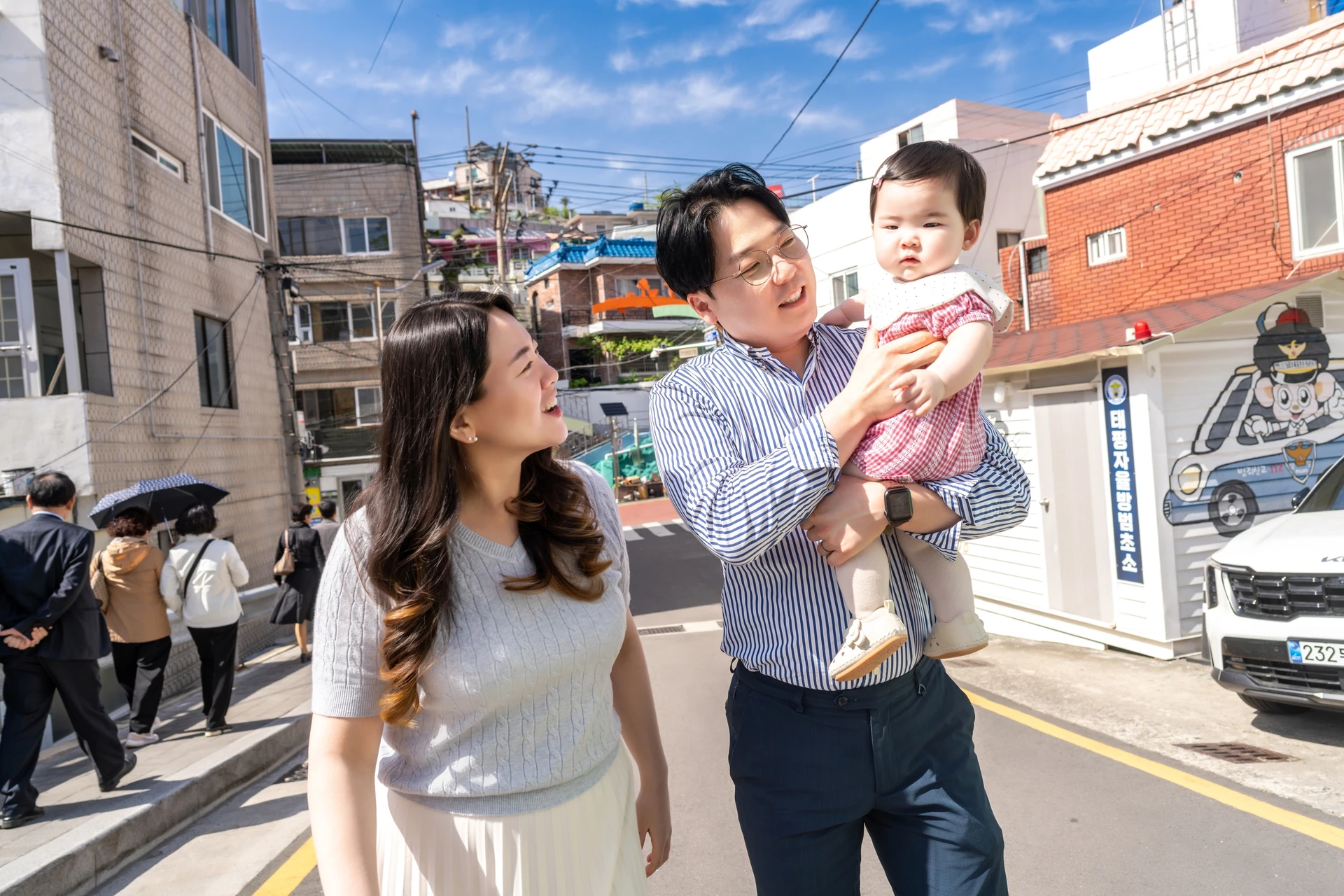 동피랑 골목길에서 아기를 안고 웃으며 걷는 아빠와 엄마