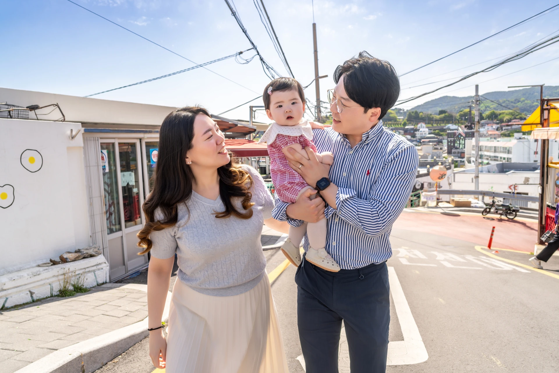 동피랑 길 위에서 아기를 안고 카메라를 바라보는 부모