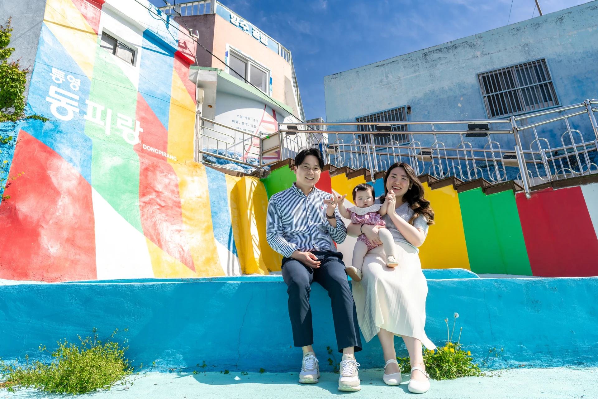 동피랑 입구 알록달록한 벽화 계단에 앉은 부부와 아기