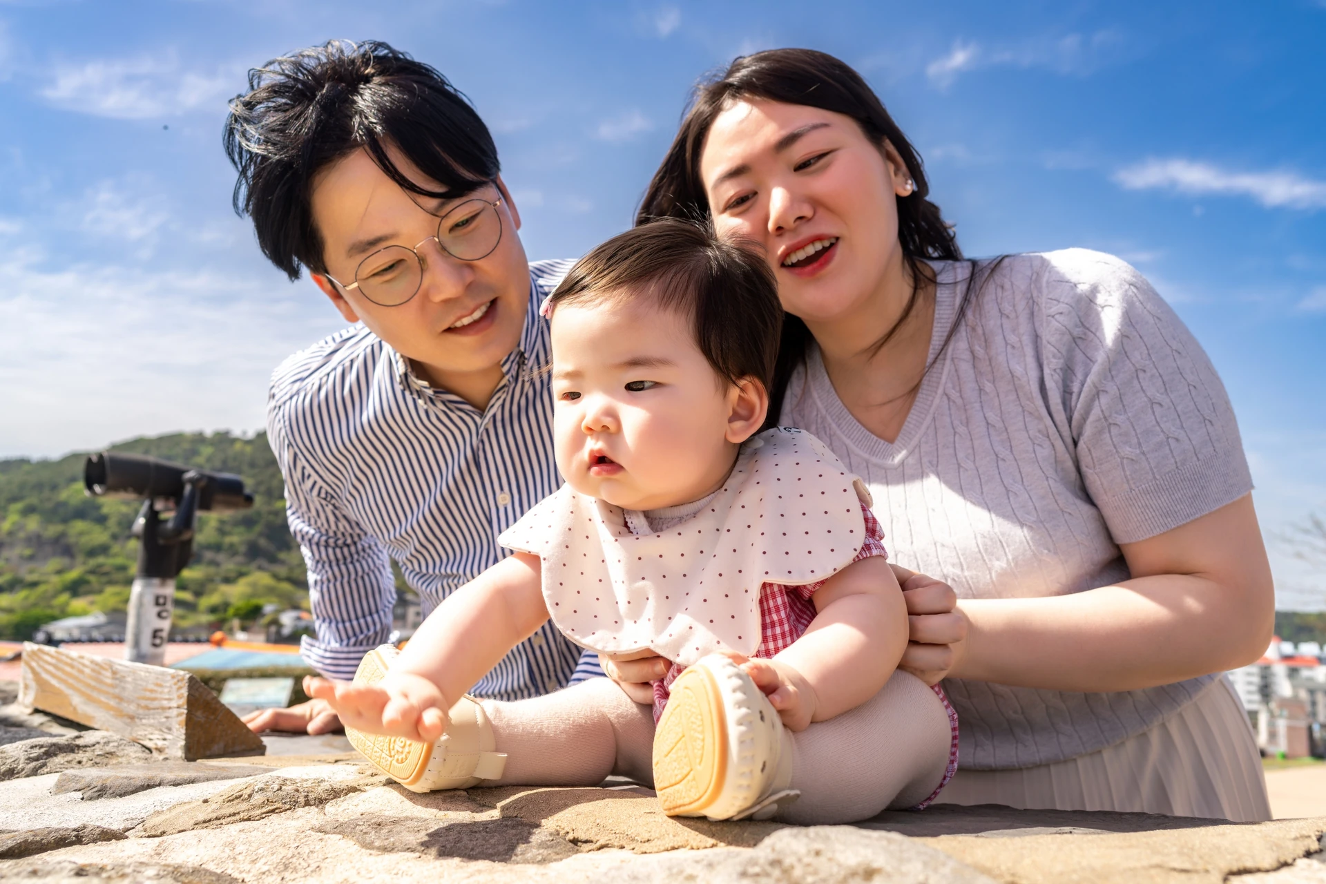 동피랑 전망대 돌 위에 앉은 아기와 양옆에서 웃는 부모