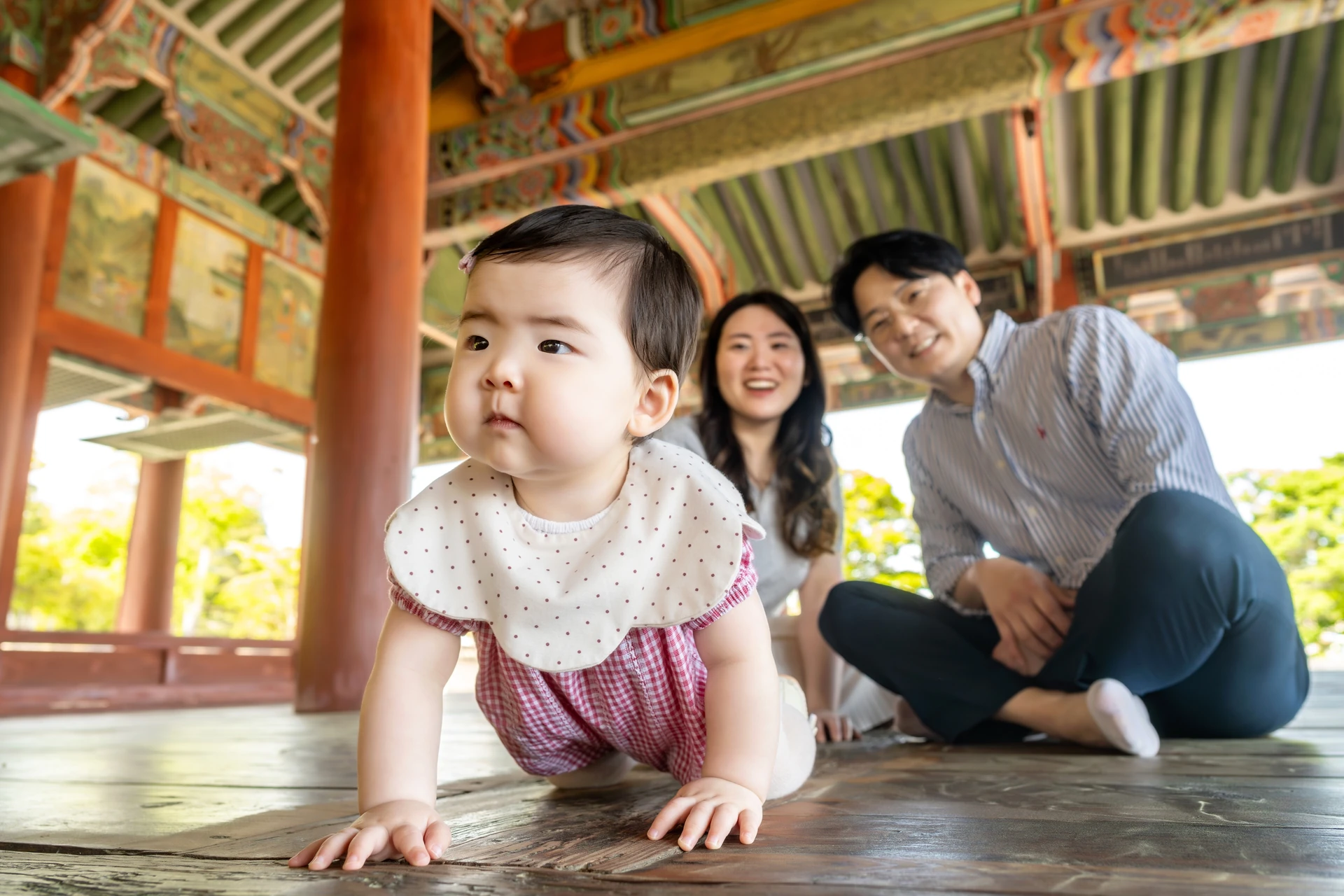 세병관 마루를 기어 오는 아기와 뒤에서 웃는 엄마와 아빠