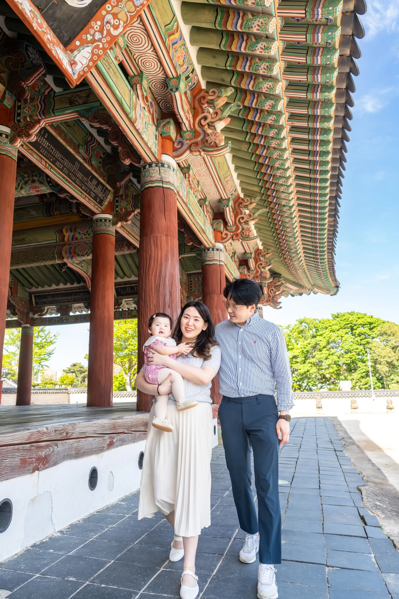 세병관 처마 아래 길을 아기를 안고 걸어오는 엄마와 아빠