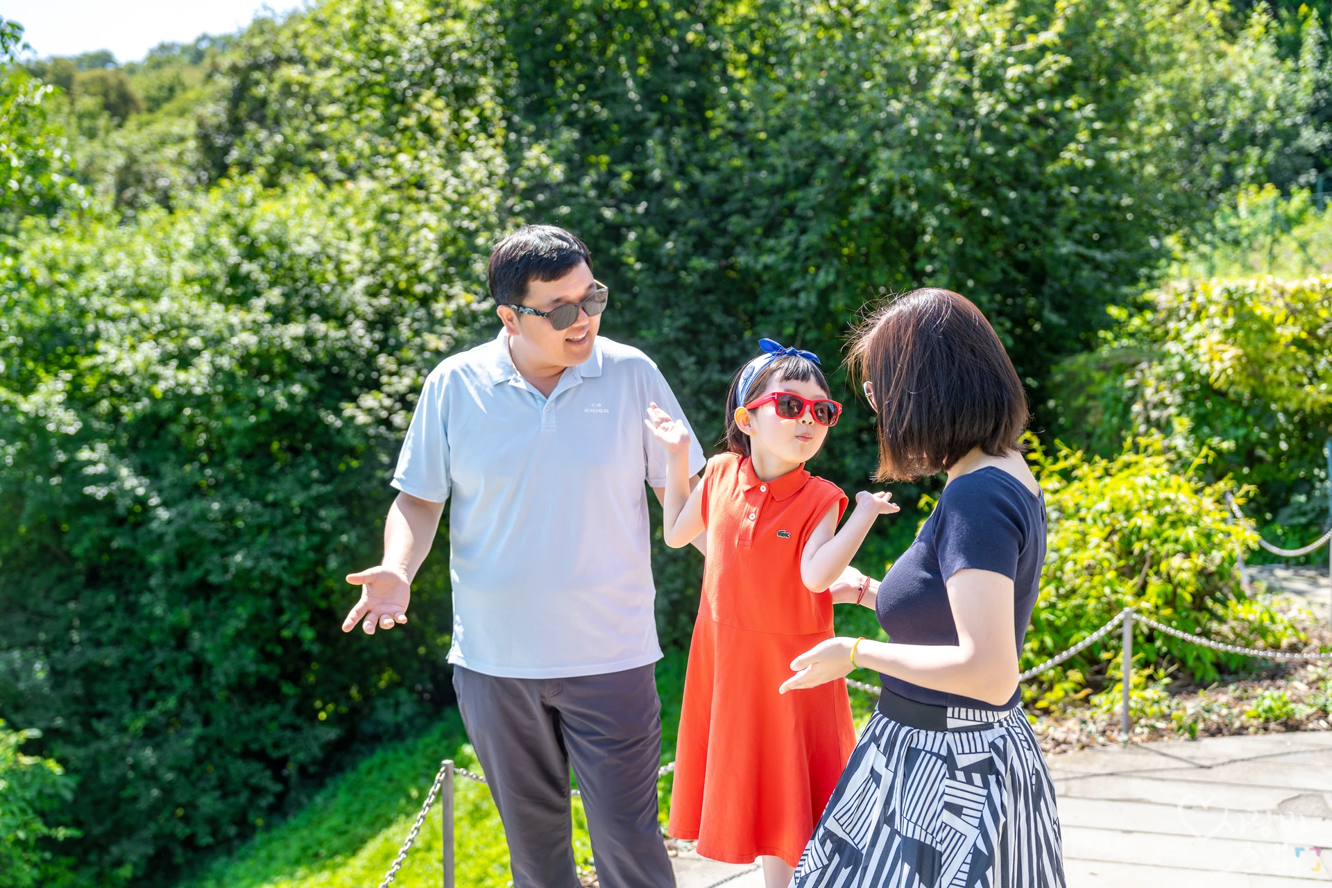 정원에서 손을 펴고 서 있는 아빠와 엄마, 아이